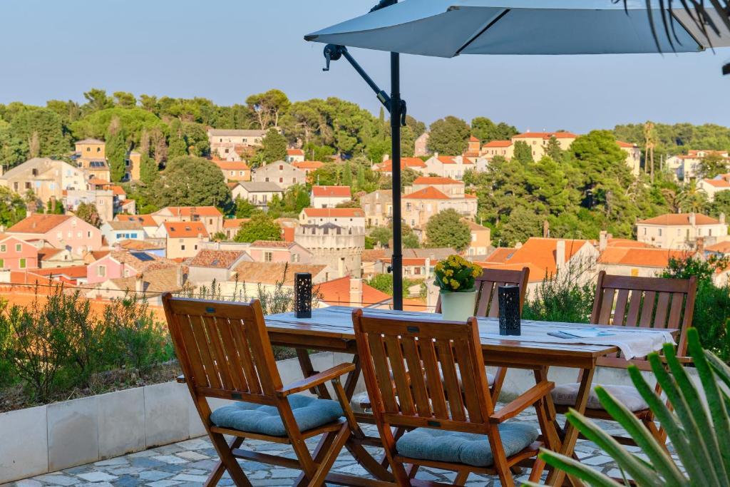 a wooden table with two chairs and an umbrella at Apartment Pepermint - near Ljubicic Tennis Academy in Veli Lošinj