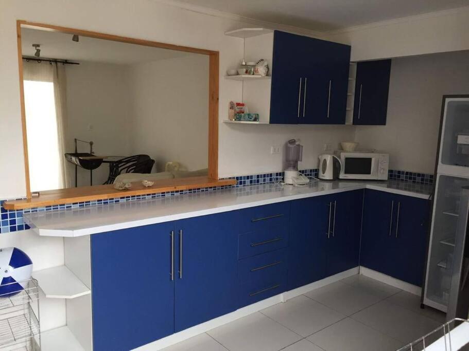 cocina con armarios azules y microondas en Casa de dos pisos a pasos de la playa, en Bahía Inglesa