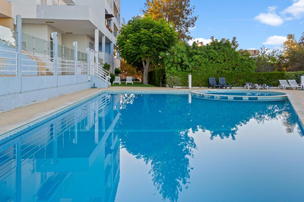 a swimming pool with blue water in front of a building at T2 Maralvor in Alvor