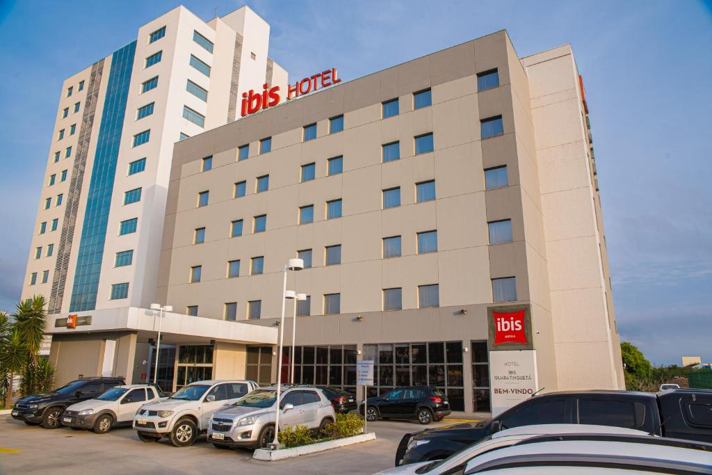 Un hotel con coches aparcados en un estacionamiento. en Ibis Guaratingueta Aparecida - Circuito da Fé, en Guaratinguetá