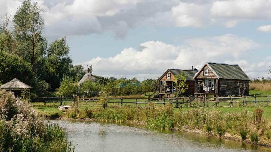 a house in a field next to a river at Lake View Lodges in Long Melford