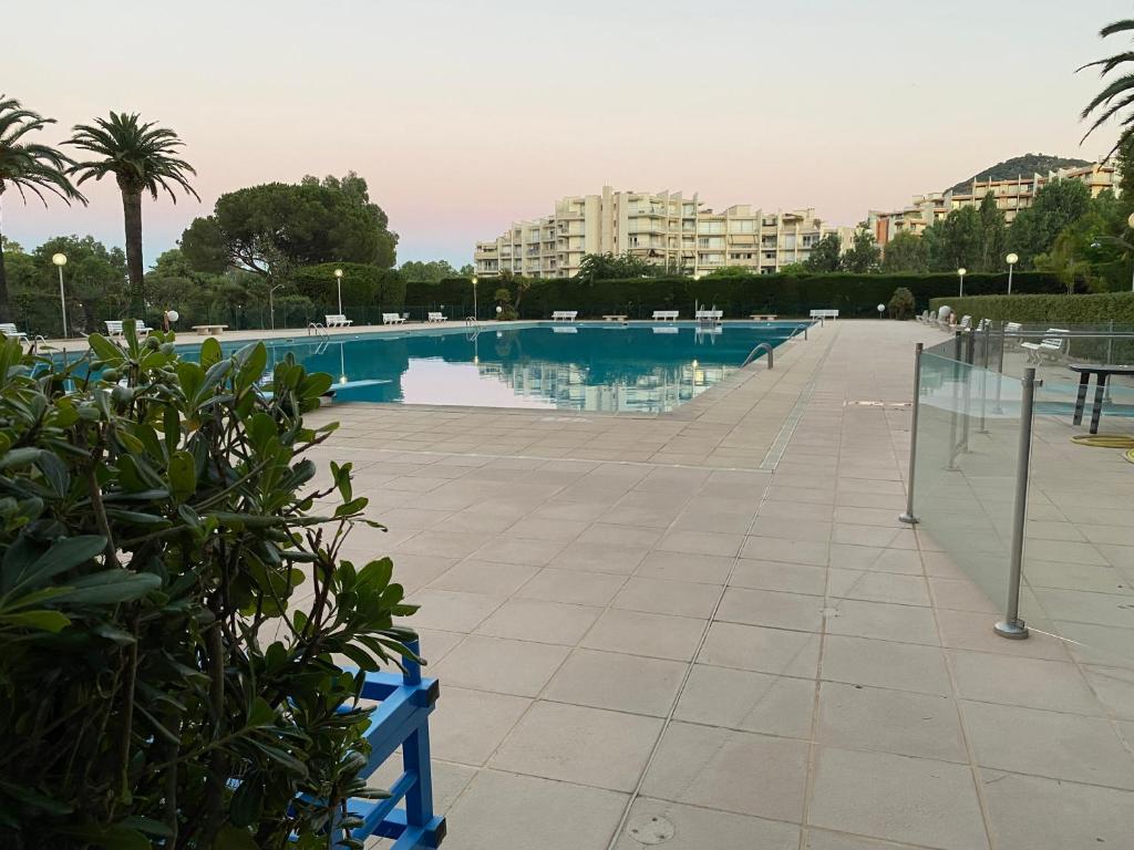 une piscine avec des chaises et des bâtiments en arrière-plan dans l'établissement Studio Cannes Marina Mandelieu, à Mandelieu-la-Napoule