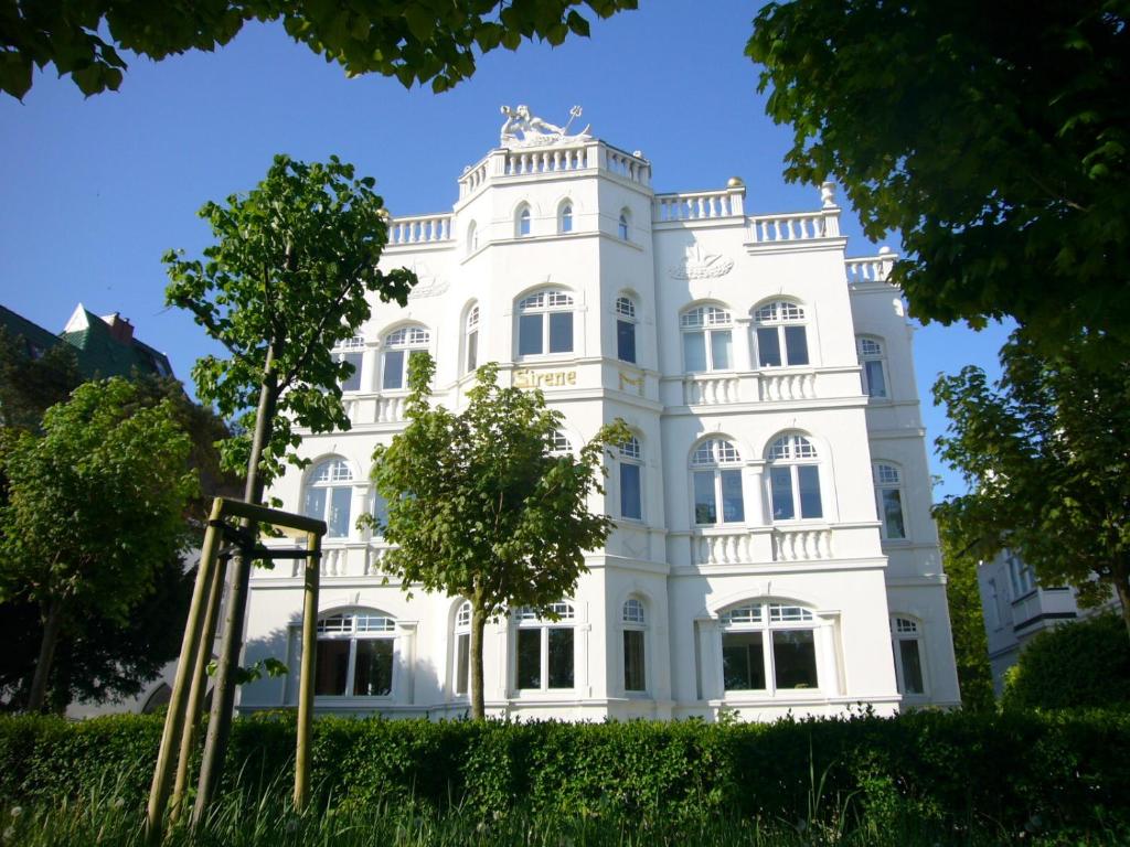 a white building with a tree in front of it at FeWos direkt am Strand, teilweise mit Meerblick, Villa Sirene, Binz in Binz