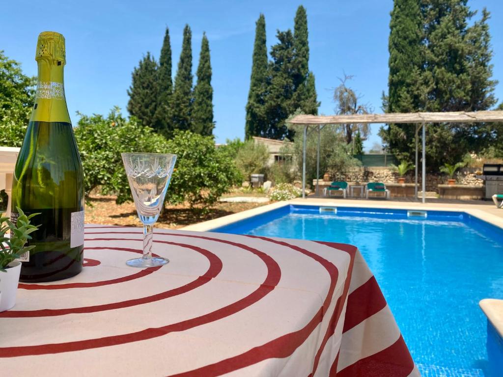 una botella de vino y una copa en una mesa junto a la piscina en Can Biel, en Pina