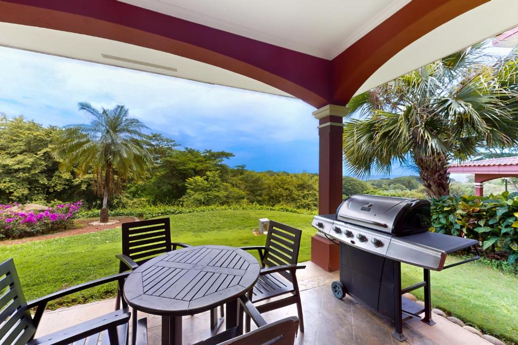 un patio con parrilla, mesa y sillas en Bougainvillea 2101 en Playa Conchal