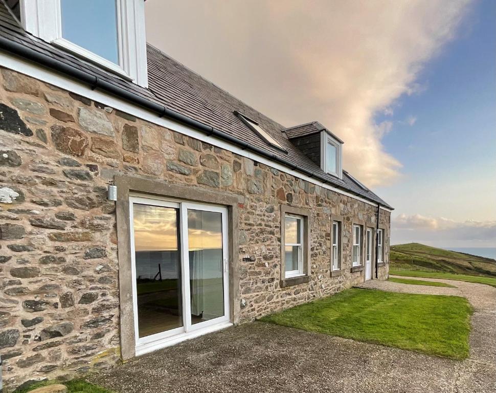 a stone house with large windows on the side of it at Bracken Cottage in Killean