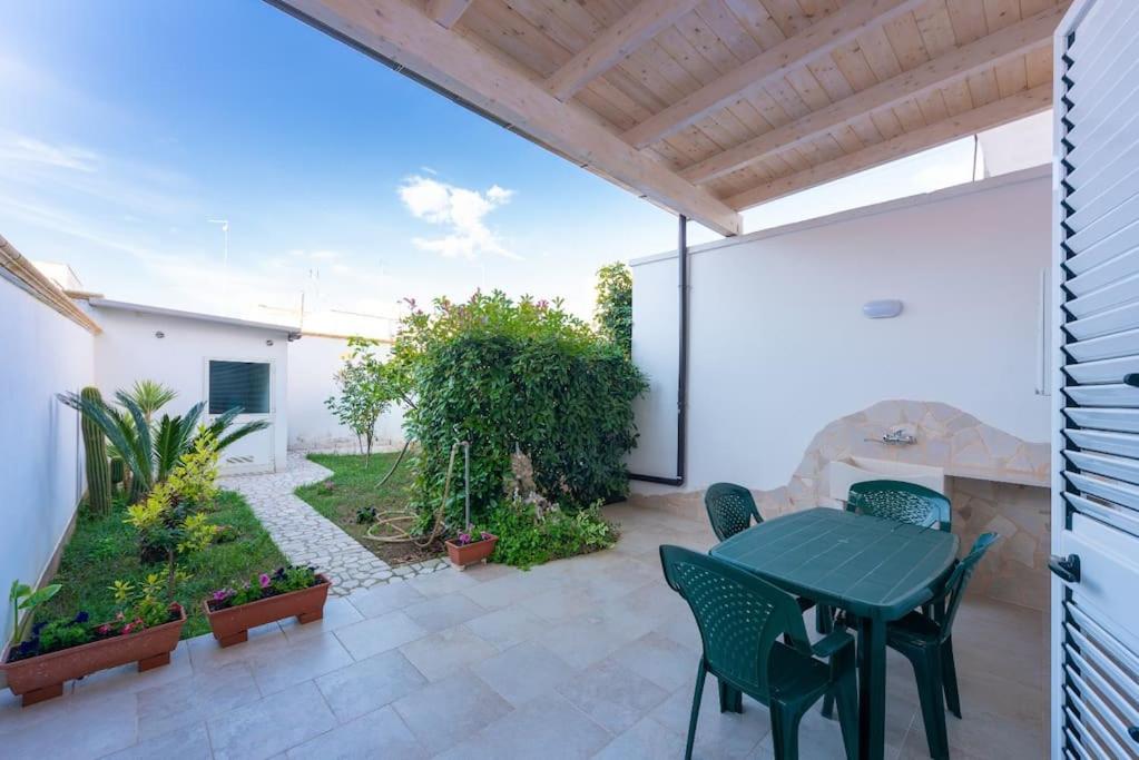 um pátio com uma mesa verde e cadeiras em La casa di nonno Mario, Salento em Magliano