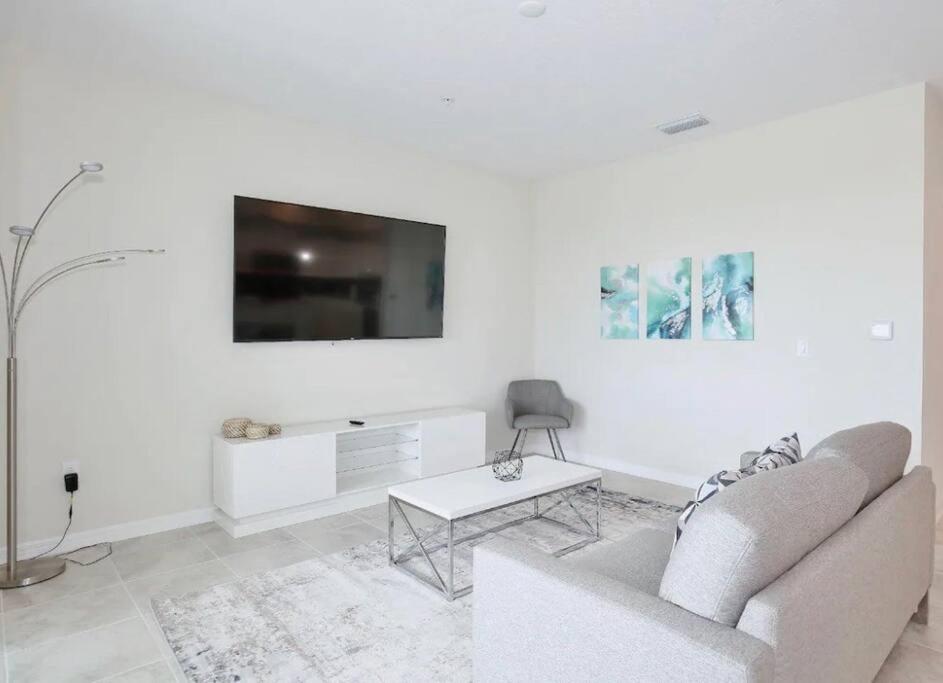 a white living room with a couch and a tv at A Luxurious Getaway Key Location in Orlando