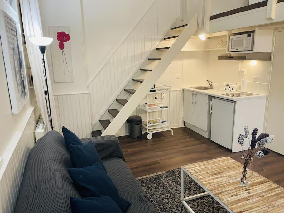 un salon avec un canapé et un escalier dans l'établissement Le Ptit Parisien - Champs Élysées - Métro & Wifi, à Paris
