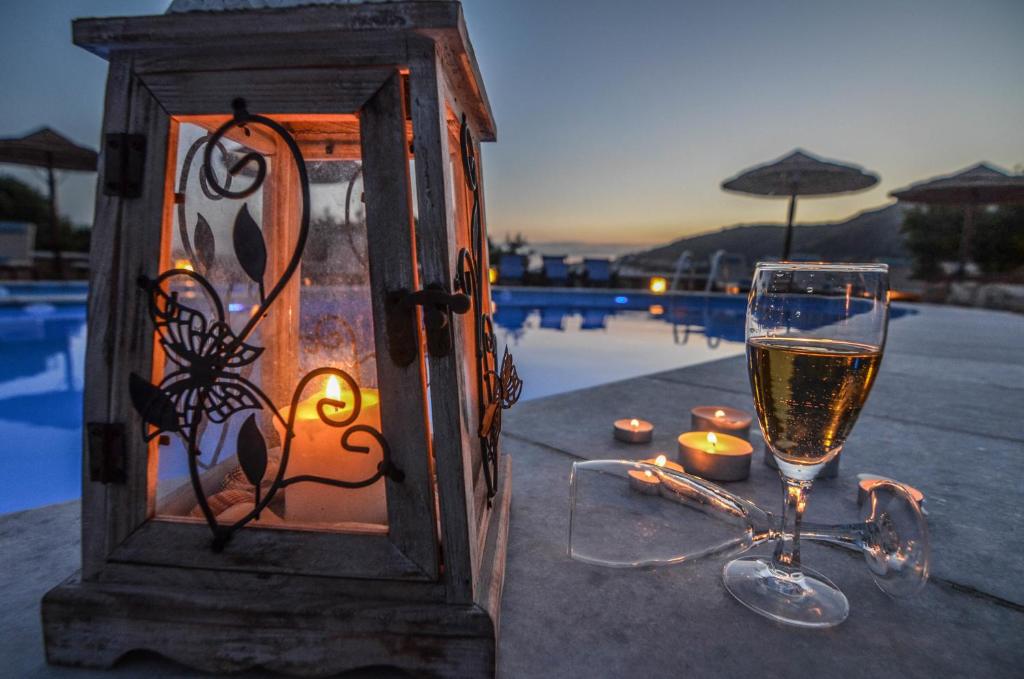 ein Glas Wein und Kerzen auf einem Tisch neben dem Pool in der Unterkunft Villa Anna Maria in Mylopotas