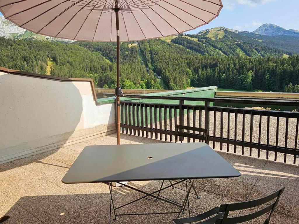 a table and chair with an umbrella on a balcony at Studio Villard-de-Lans, 1 pièce, 4 personnes - FR-1-515-106 in Villard-de-Lans