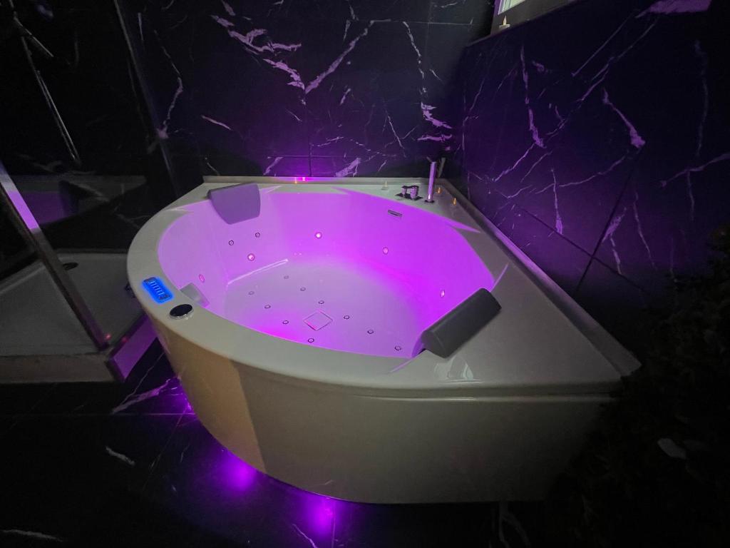 a purple bath tub with purple lights in a bathroom at Escapade Urbaine - Balnéothérapie - Cinéma au Cœur de la Ville in Mâcon
