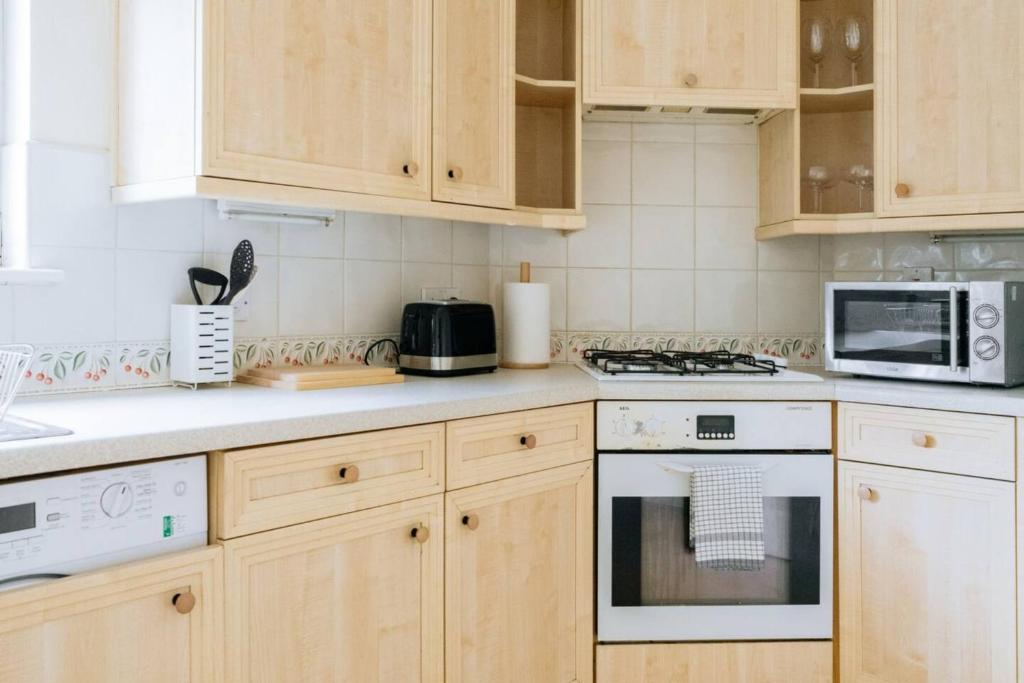 a kitchen with wooden cabinets and a stove top oven at Snug & Serene 2BD Flat - Roseburn in Edinburgh