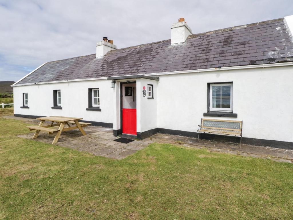 Cabaña blanca con puerta roja y mesa de picnic en Sound Cottage en Sraheens