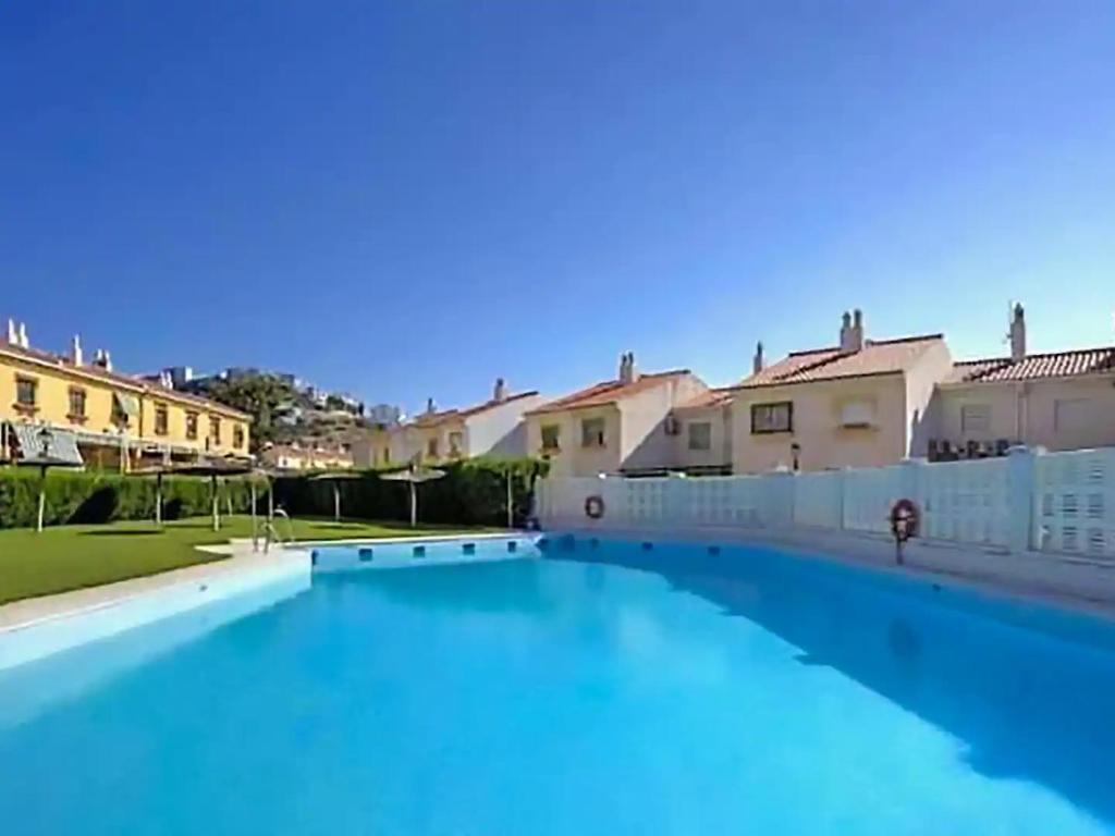 a large blue swimming pool with houses in the background at Casa del Sol in Salobreña