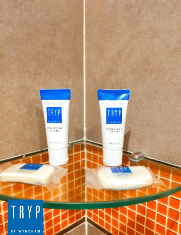 two white and blue products on a glass shelf at TRYP BY WYNDHAM São Paulo Airport - Hotel de Transito Terminal 3 -Lado Ar - Área restrita á passageiros já embarcados - Piso 1 in Guarulhos
