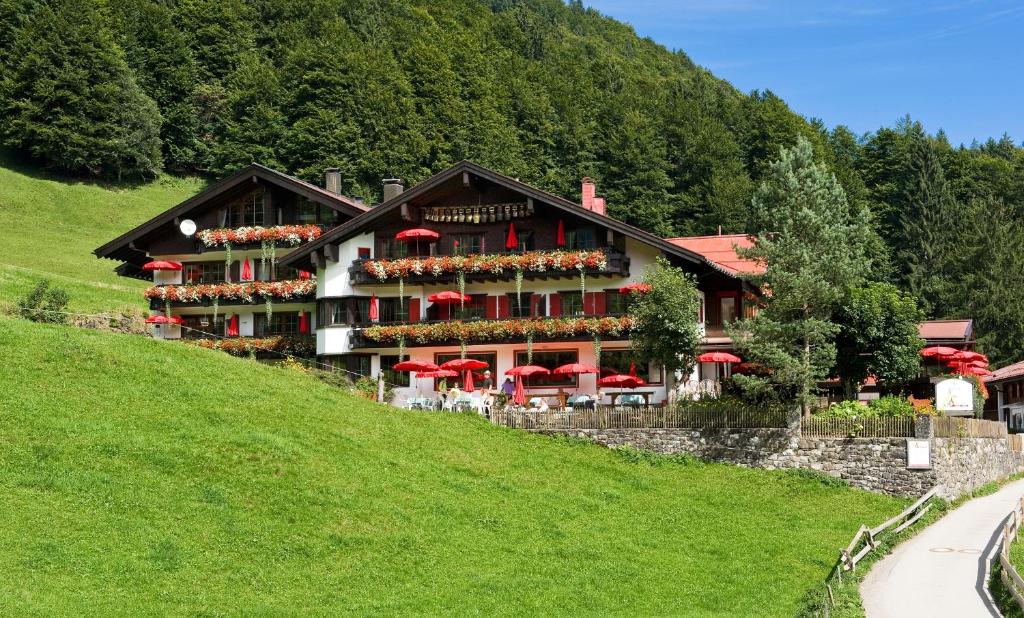 a building on a hill with red umbrellas at Alpengasthof Hotel Schwand in Oberstdorf