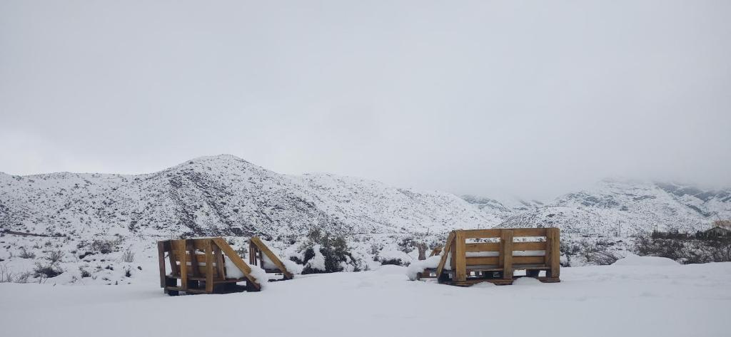 deux bancs assis dans la neige avec des montagnes en arrière-plan dans l'établissement Esencia Cabaña, à Potrerillos