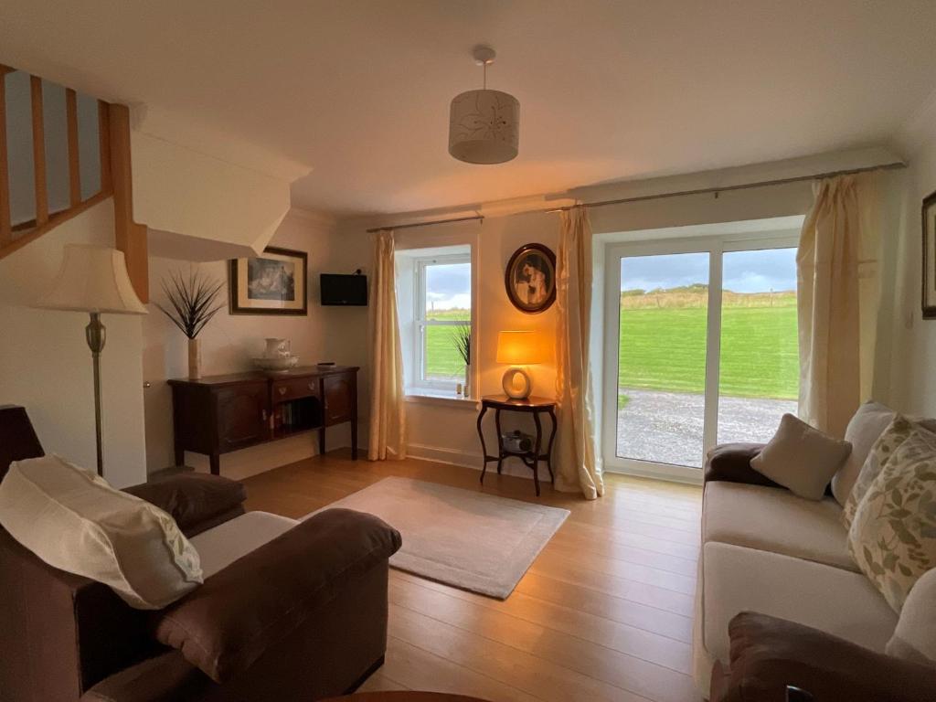 a living room with a couch and a window at Buttercup Cottage in Killean