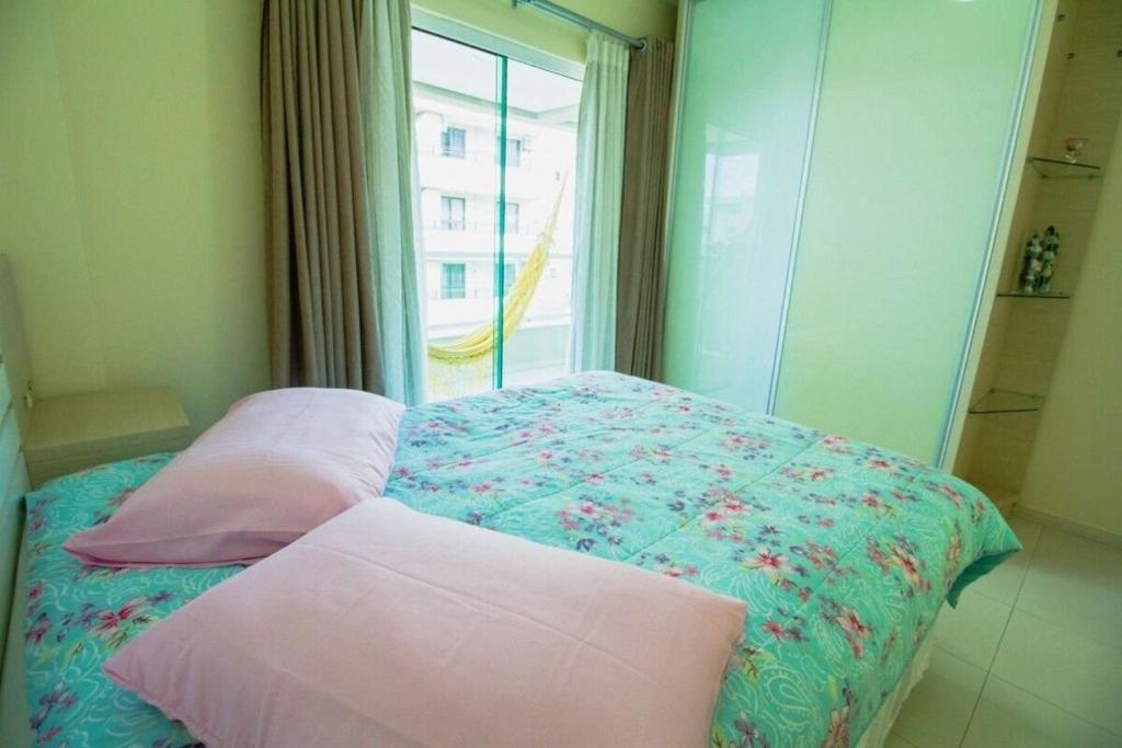 a bedroom with a bed with pillows and a window at 201- Apartamento Bombas com vista lateral do mar in Bombas