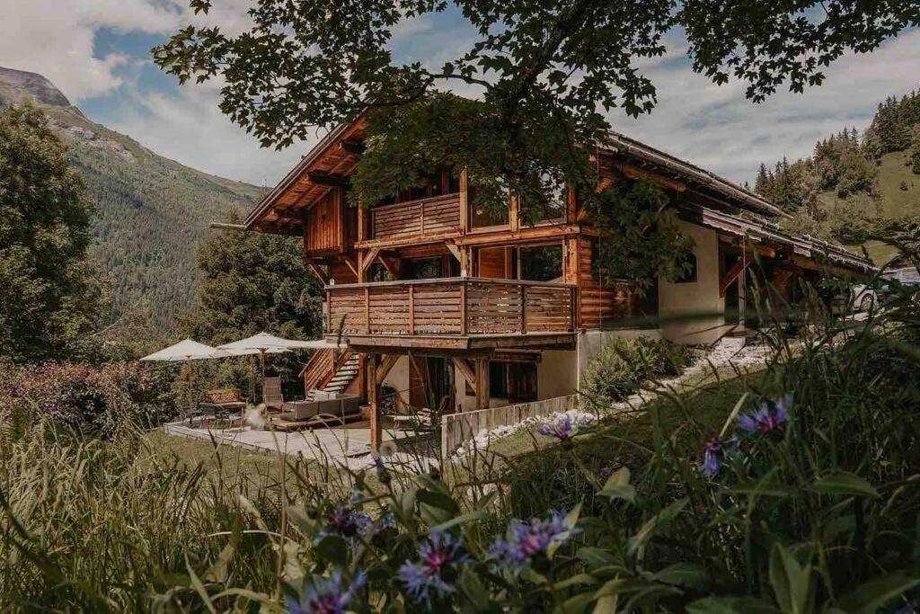 a log cabin in the mountains with flowers in front of it at Superbe CHALET (14 personnes) & SAUNA au pied du Mont Blanc in Les Contamines-Montjoie