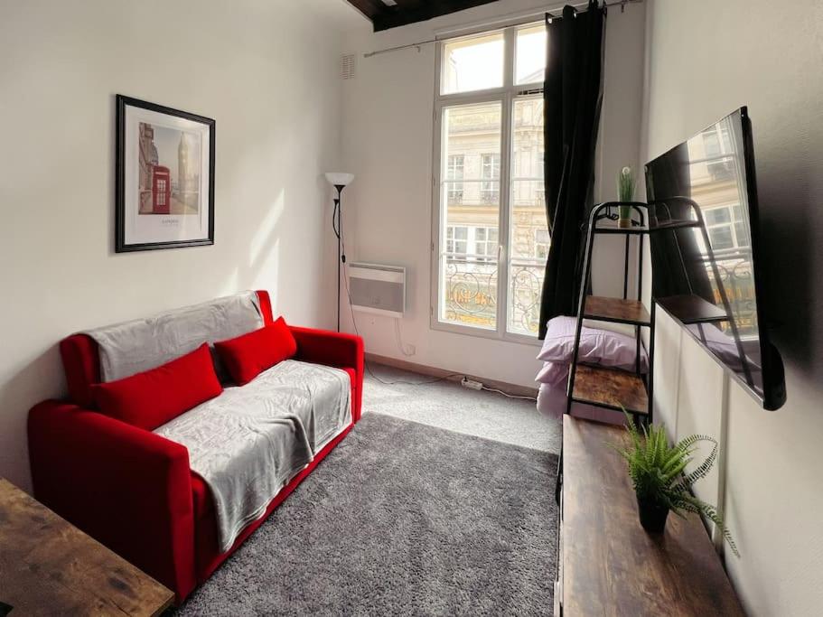 a living room with a red couch and a window at Cosy Appart Centre de Paris in Paris