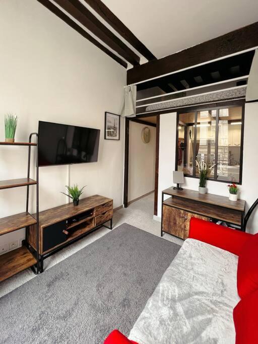 Il comprend un salon doté d'un canapé rouge et d'une télévision à écran plat. dans l'établissement Cosy Appart Centre de Paris, à Paris