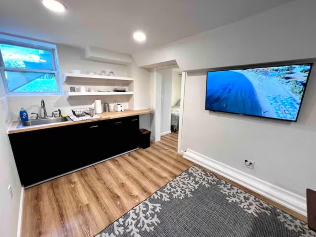 a kitchen with a sink and a flat screen tv on a wall at Modern Studio in Norwalk in Norwalk