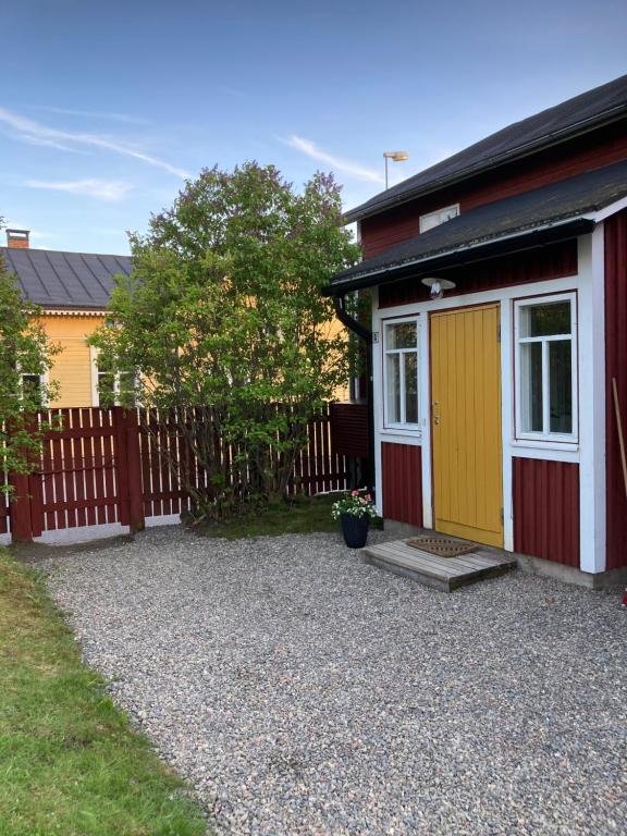 a small house with a yellow door and a fence at Lönngården in Kristinestad