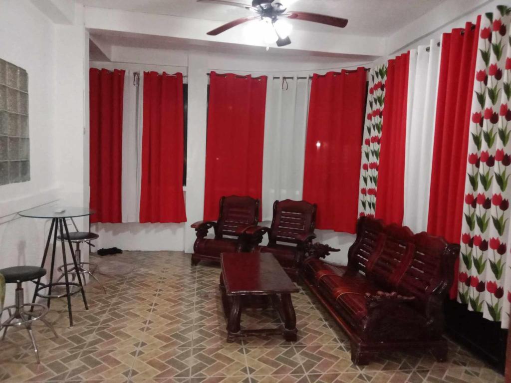 un soggiorno con tende rosse e bianche e un divano di 4jMarte Home Stay a Imus