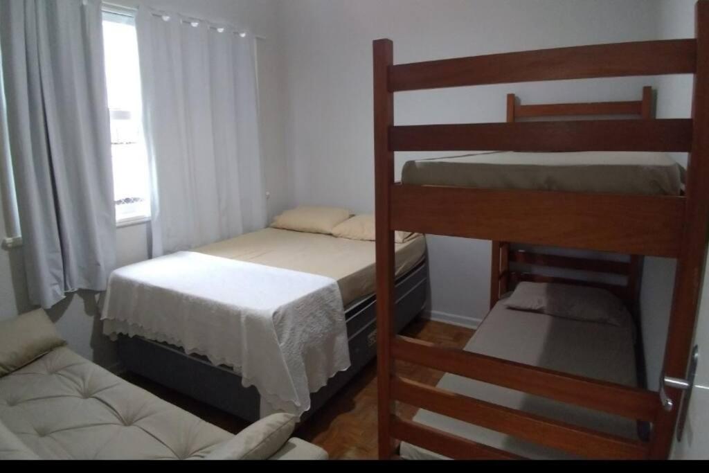 um pequeno quarto com 2 beliches e um sofá em Apartamento Pé na Areia na Praia das Pitangueiras no Guarujá