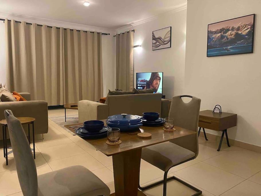 ein Wohnzimmer mit einem Tisch und einem Sofa in der Unterkunft Homely 2-Bedroom at Victoria Place in Daressalam