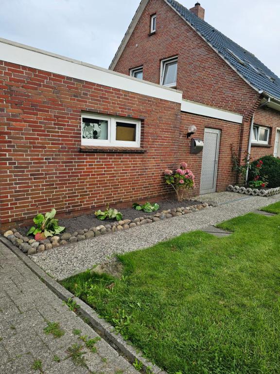 a brick house with a garden in front of it at Ferienwohnung Mond&Wasser 2 in Norden