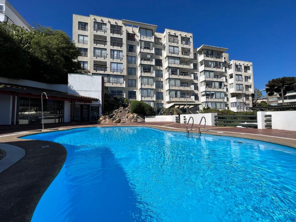 una gran piscina azul frente a un edificio en Reñaca Departamento Holiday Park 605 cómodo y buena ubicación familiar, en Viña del Mar