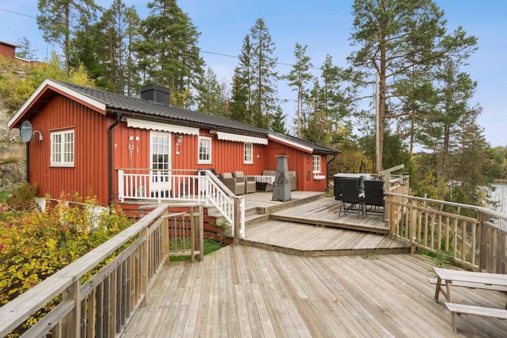 une cabine rouge avec une terrasse et une maison dans l'établissement Familievennlig hytte ved populært badevann!, à Sandefjord