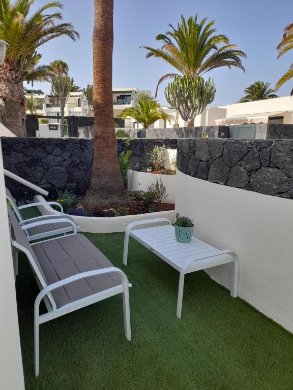 a group of chairs and a table on a patio at Bungalow Paseo del Mar- PLAYA ROCA Residence sea front access - Free AC - Wifi in Costa Teguise