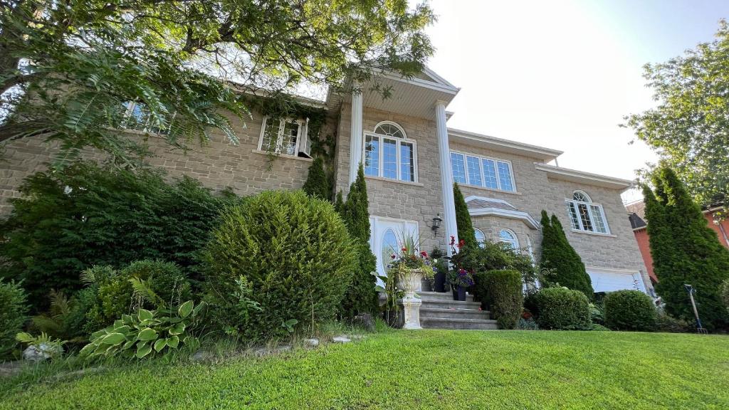 una gran casa de ladrillo con un patio de hierba en Gîte du Caméléon en Sherbrooke