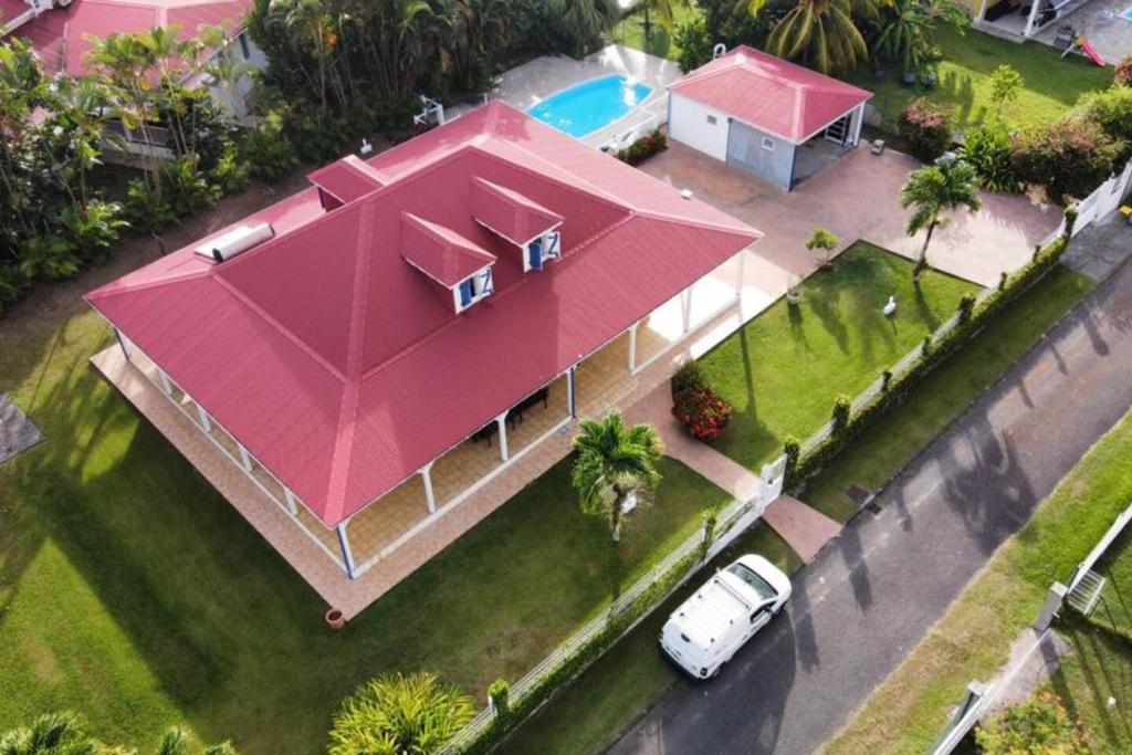 une maison avec un grand toit rose dans une rue dans l'établissement BluePalm case, à Petit-Bourg