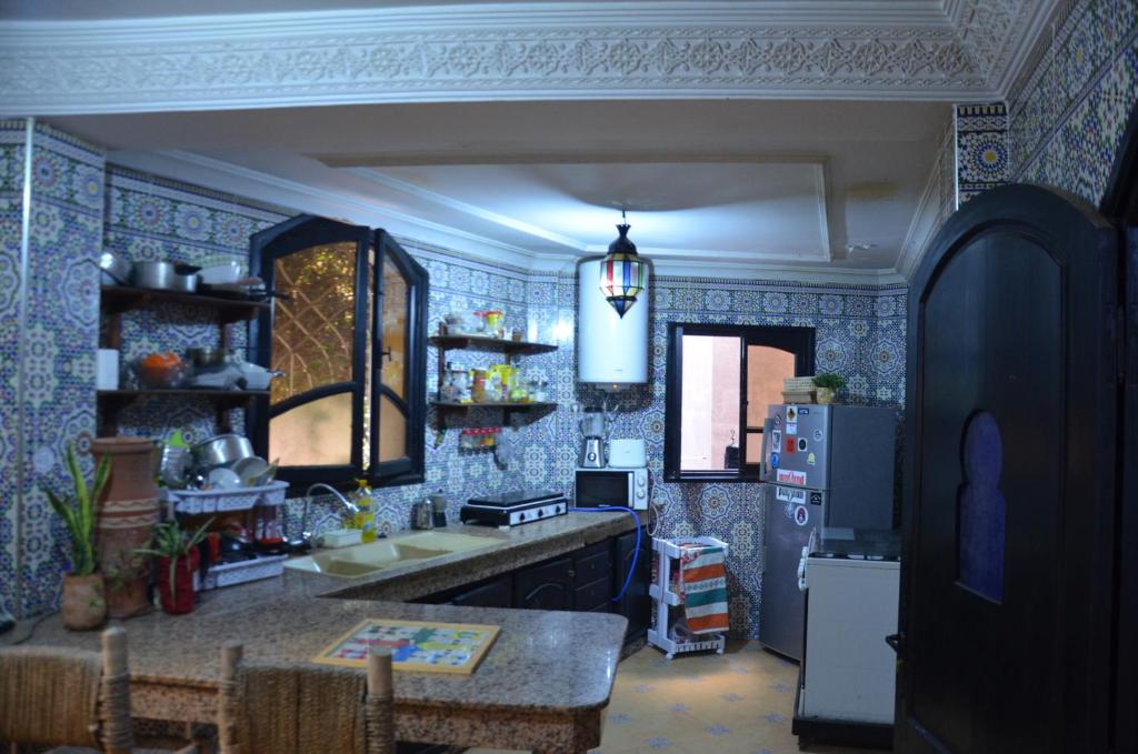una cucina con pareti piastrellate blu e frigorifero di Arima Surf House a Tamraght Ouzdar