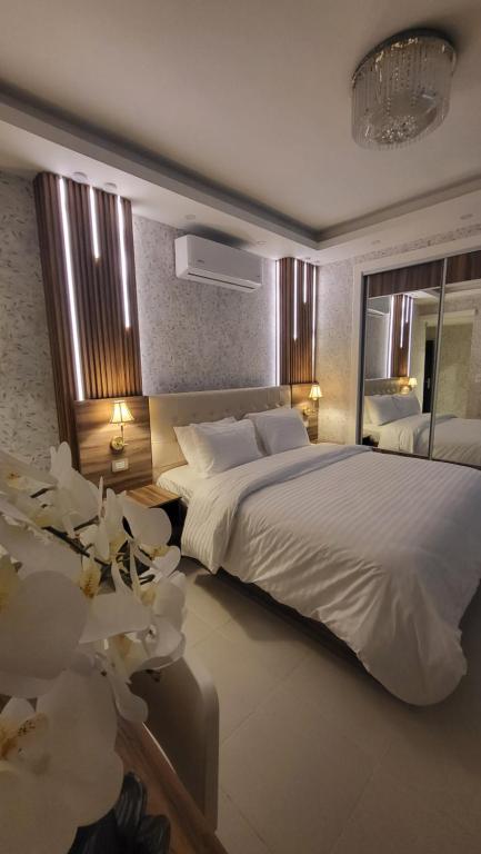 a bedroom with a large white bed and a mirror at Western Gate Residence 1 - Amman, Jordan in Amman
