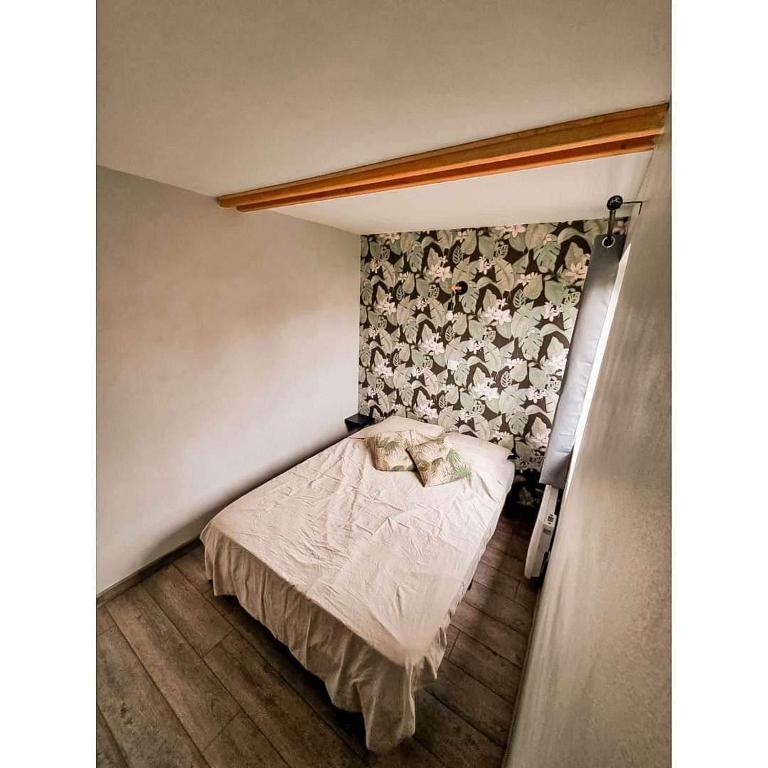 - une petite chambre avec un lit et un mur fleuri dans l'établissement Chalet colonids 2, à Grues