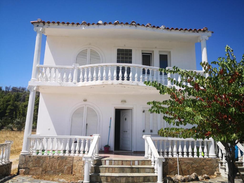 une maison blanche avec un balcon blanc et des escaliers. dans l'établissement Παραθαλάσσια εξοχική κατοικία, à Vasilika