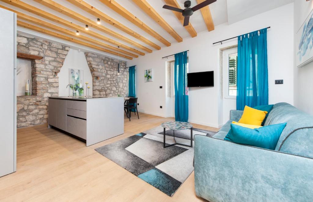 ein Wohnzimmer mit einem blauen Sofa und einer Küche in der Unterkunft Casa Rosa 1 in Rovinj