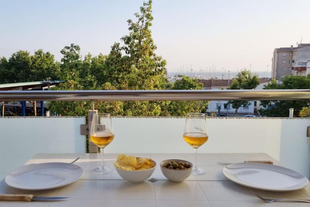 uma mesa com dois copos de vinho e uma taça de comida em Piso en el centro con vistas al mar y balcón em Roses