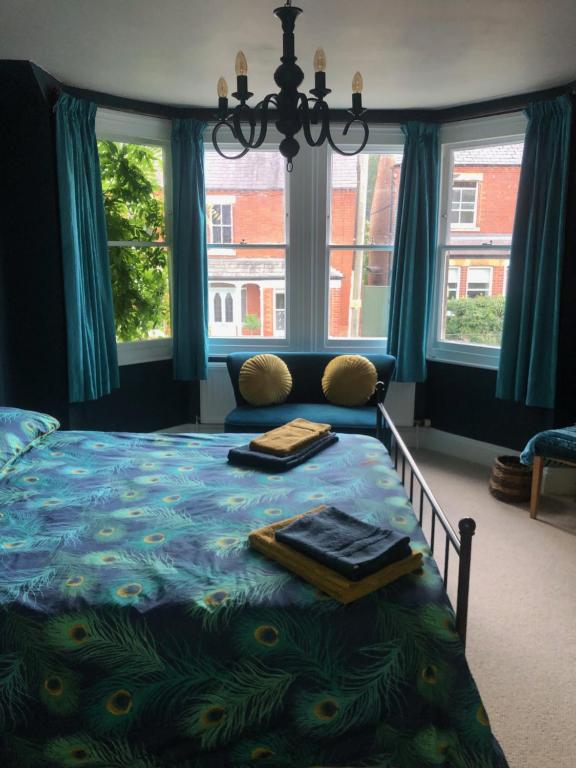 a bedroom with a bed with blue curtains and windows at Balcarres, Rodborough Avenue in Stroud