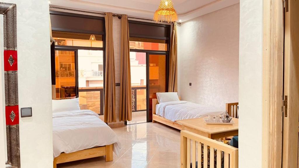 1 dormitorio con 2 camas, mesa y balcón en WOW beach house en Imsouane