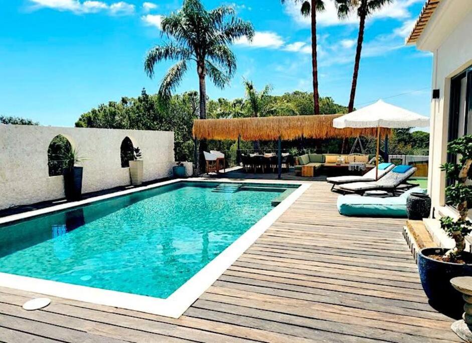 - une piscine avec une terrasse en bois à côté d'une maison dans l'établissement Casa Chameleon, à Almancil
