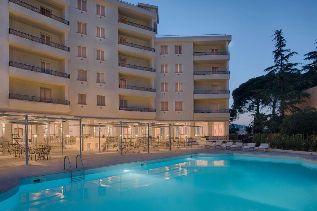 a hotel with a swimming pool in front of a building at NH Caltagirone Villa San Mauro in Caltagirone