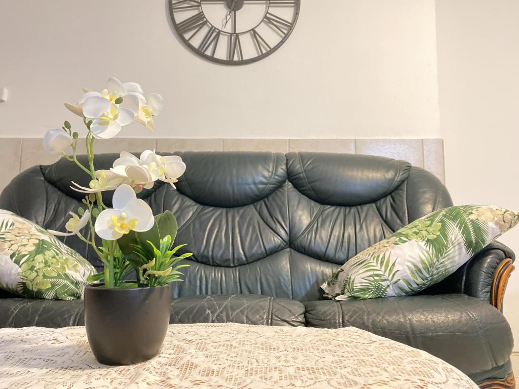 un canapé en cuir avec une table et un vase avec des fleurs dans l'établissement KAZ A CYCY, à Vieux-Habitants