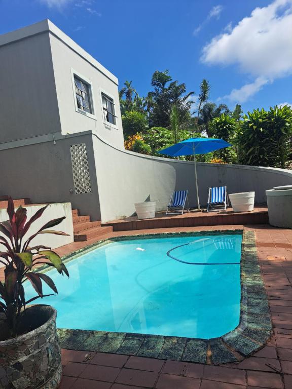 a swimming pool with two chairs and an umbrella at Manor house in Durban